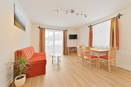 Wohnküche mit gemütlicher Couch, Esstisch und Fernseher